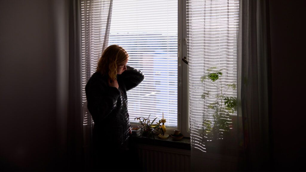 A woman with mono looking out a window.
