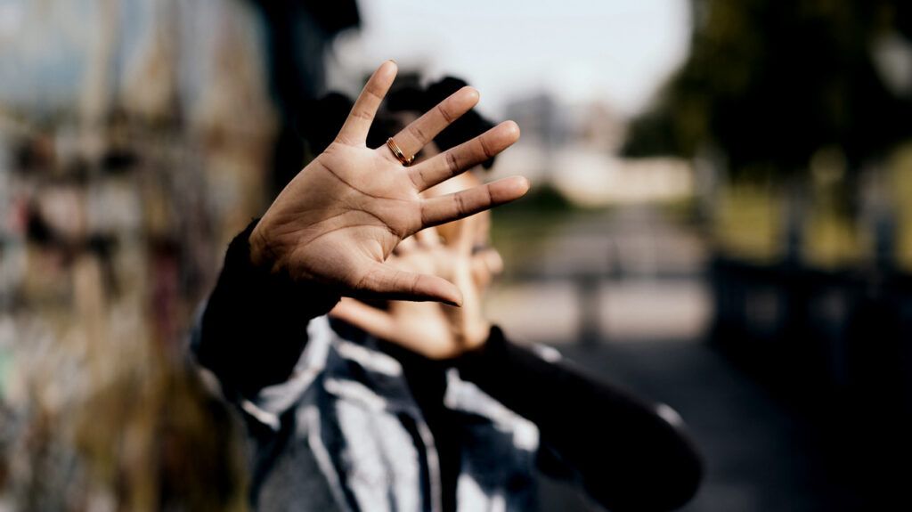 A person with rejection phobia covering their face with outstretched hands.-1