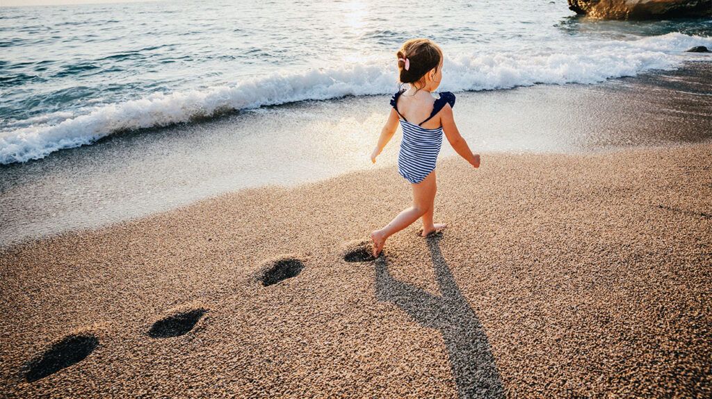 A child is walking along the beach.