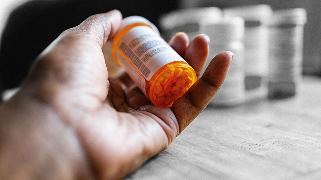 A bottle of prescription medication in a persons hand 1
