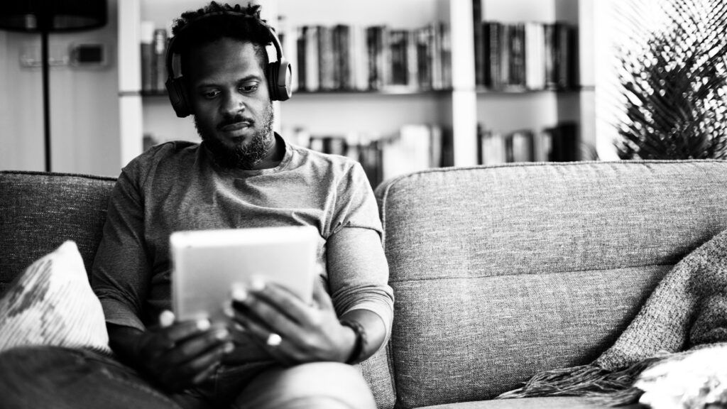 A man reads an iPad while wearing headphones