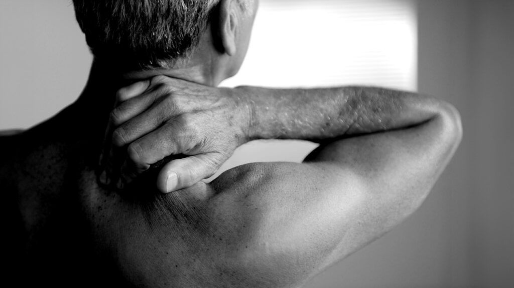 A man touching the back of his neck to depict osteoarthritis pain