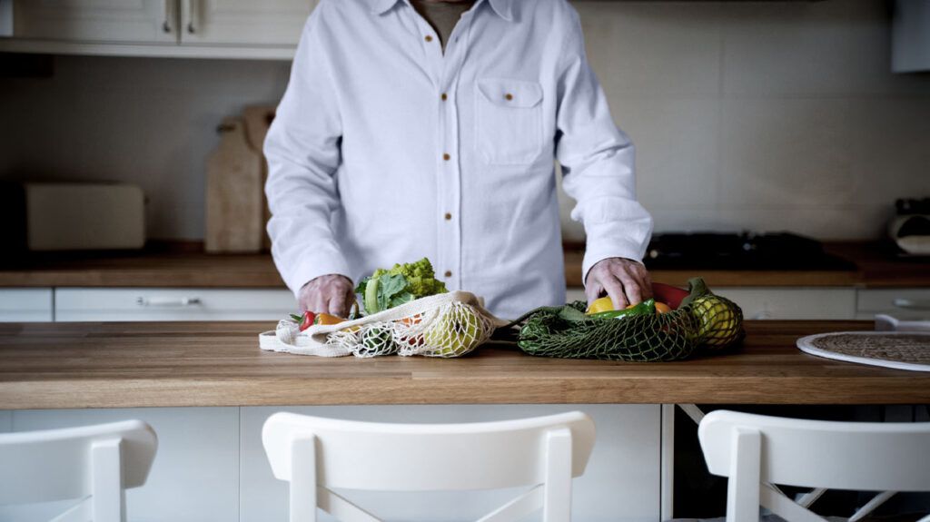 person in white buttoned down shirt preparing vegetables on a wooden tabletop