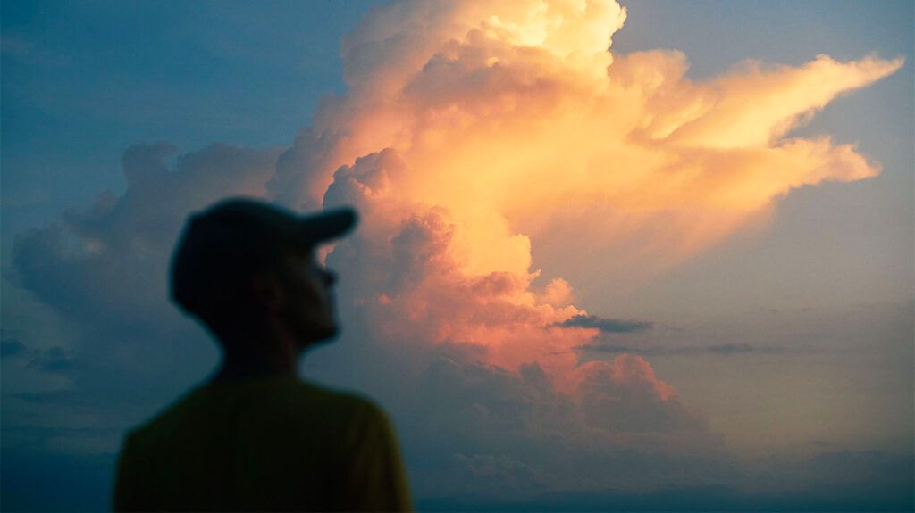 Un uomo osserva le nuvole arancioni nel cielo