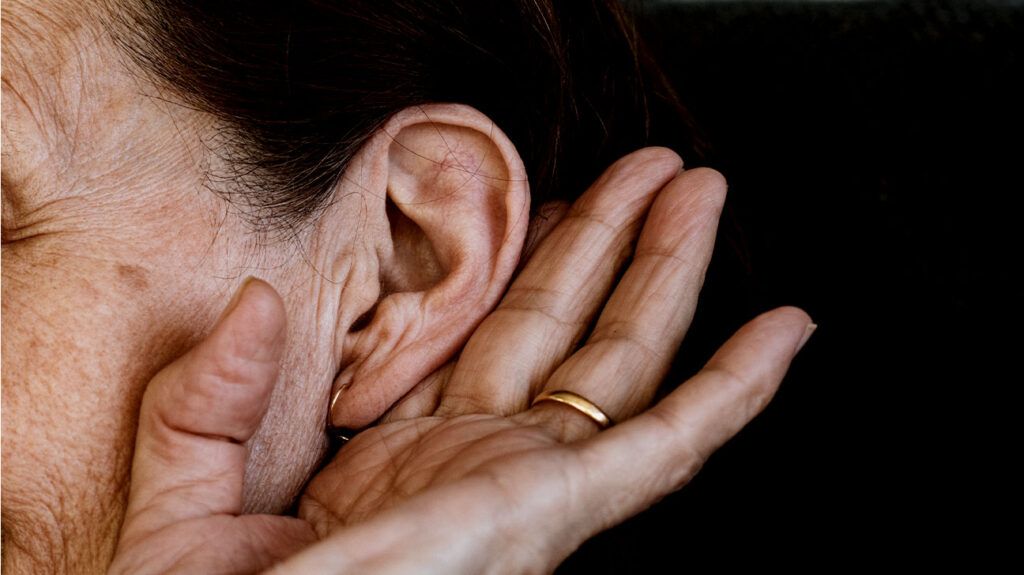 A person with tinnitus cupping their ear to hear better.-1