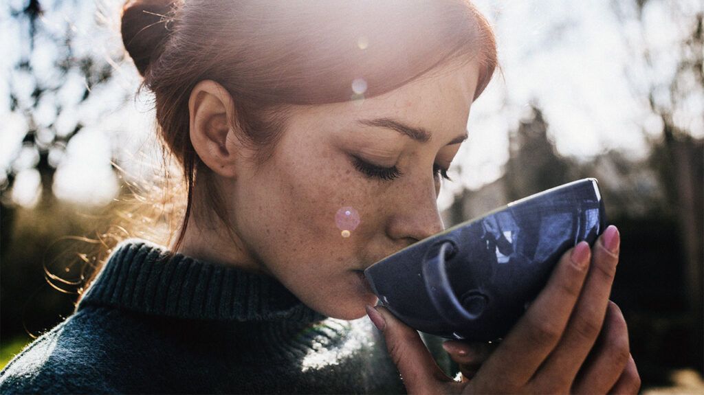 Female drinking from a mug outside