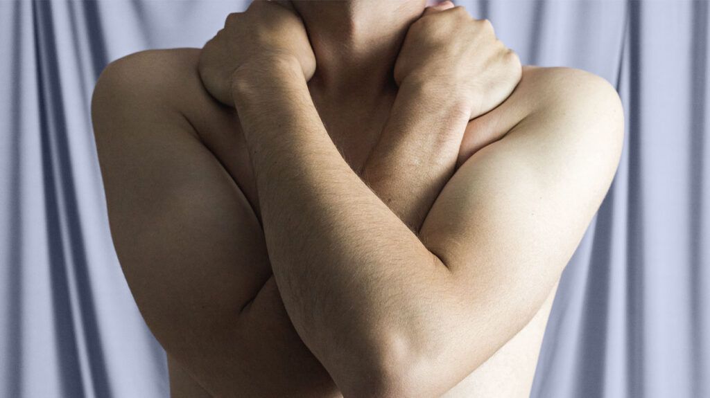 Topless male holding his arms across his body