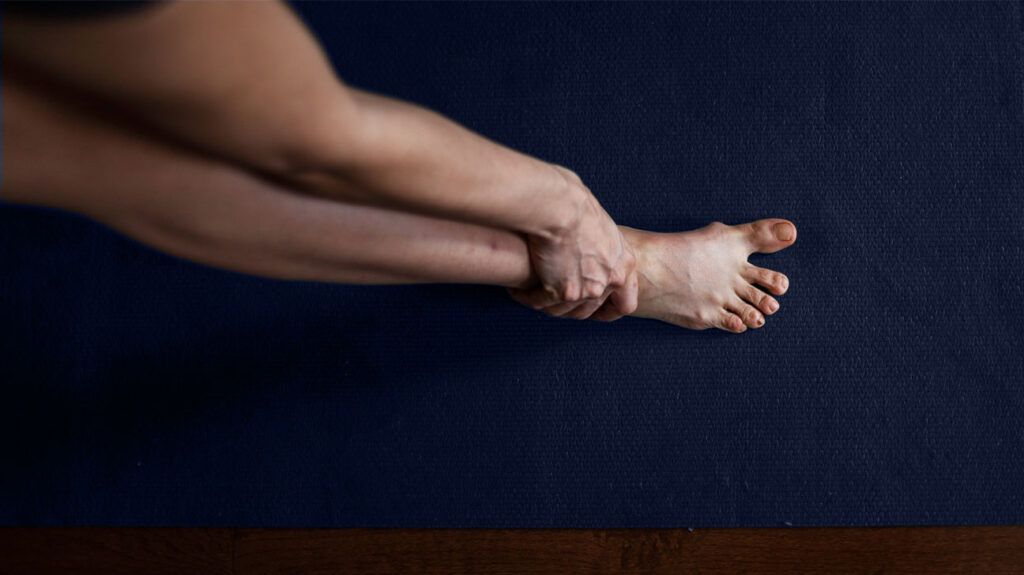 Image of a person's foot with their hand around their ankle