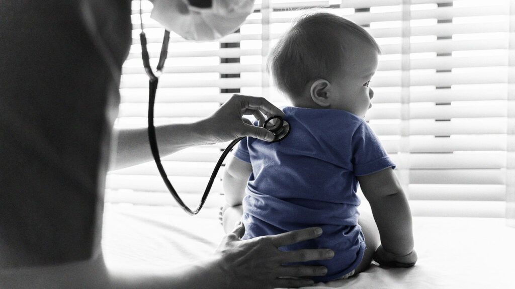 A doctor monitoring a baby for whooping cough with a stethoscope. 