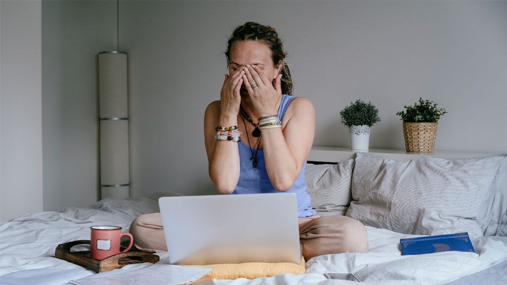 Woman with a laptop rubbing her eyes