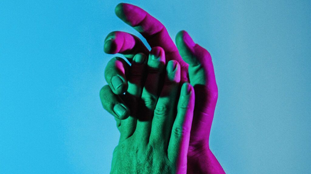 Closeup of a person's hands against a blue background.