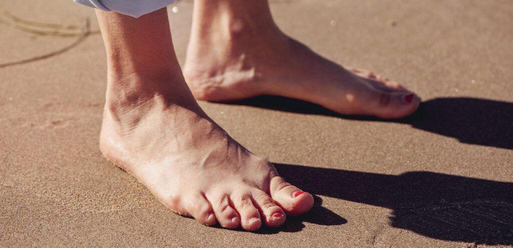 A person's bare feet on sand