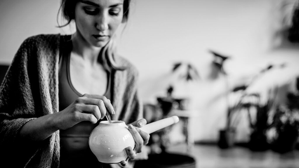 Black and white image of a female holding a neti pot