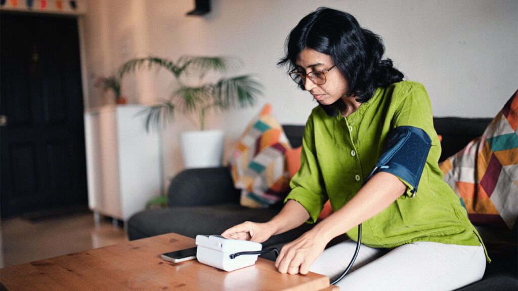 A woman using a blood pressure monitor to check her blood pressure at home. -1