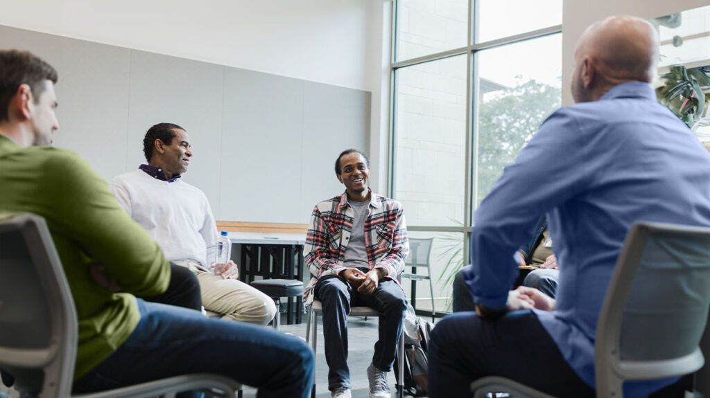 A group of men sat in a circle and talking at a support group for PTSD.