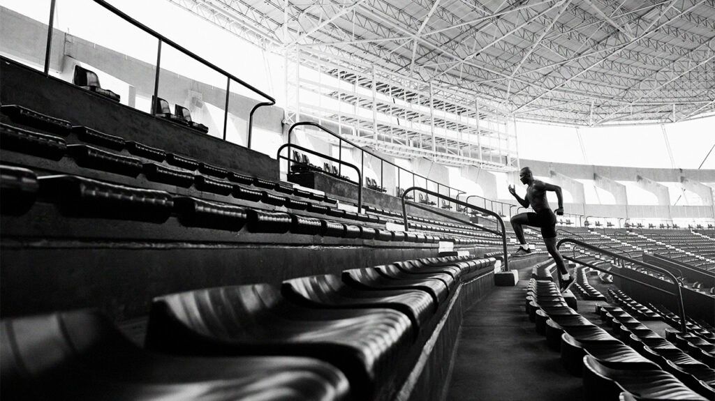 A male athlete running up the stadium chairs-1