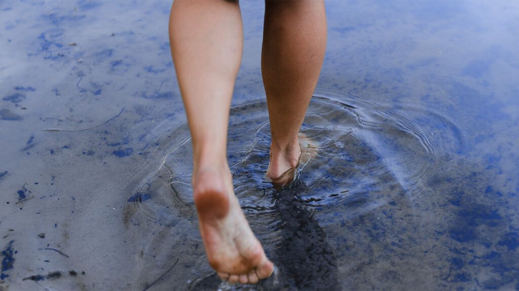 The feet of a person walking through shallow water