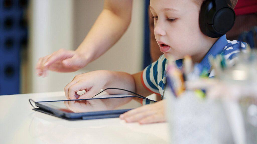 A child with auditory processing disorder using a tablet at an audiometry session.-2