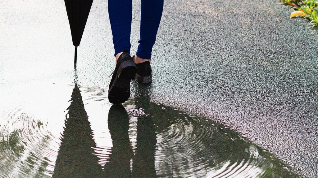 A person's feet walking through a puddle