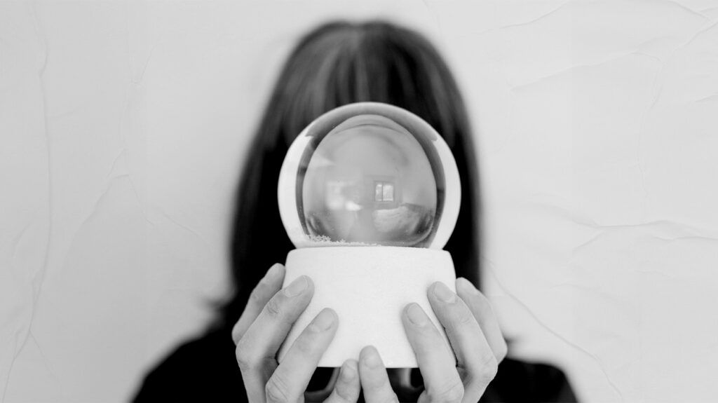 A woman holding a crystal ball, obscuring her face.