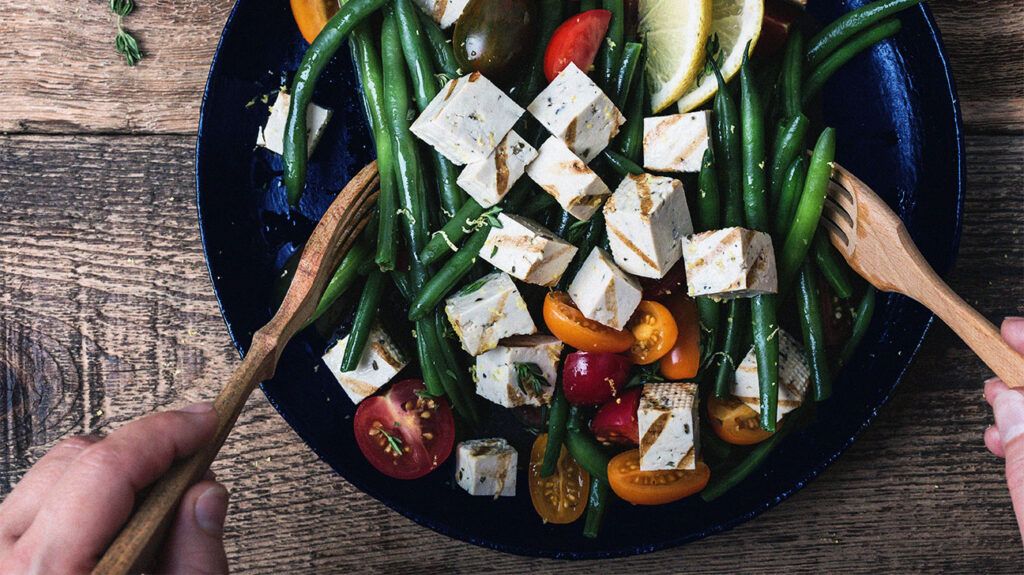 Close up of a salad with tofu, green beans and tomatoes