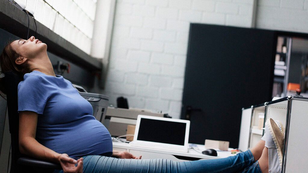 Pregnant person practising hypnobirthing meditation while sitting at a desk-1