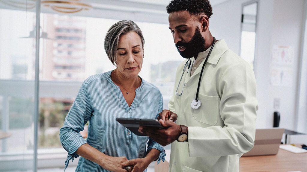 A doctor showing a patient something on a digital tablet.