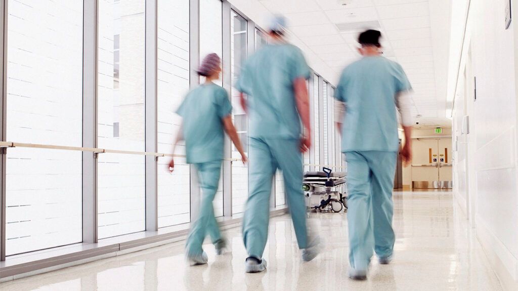 Medical professionals are walking down a corridor.