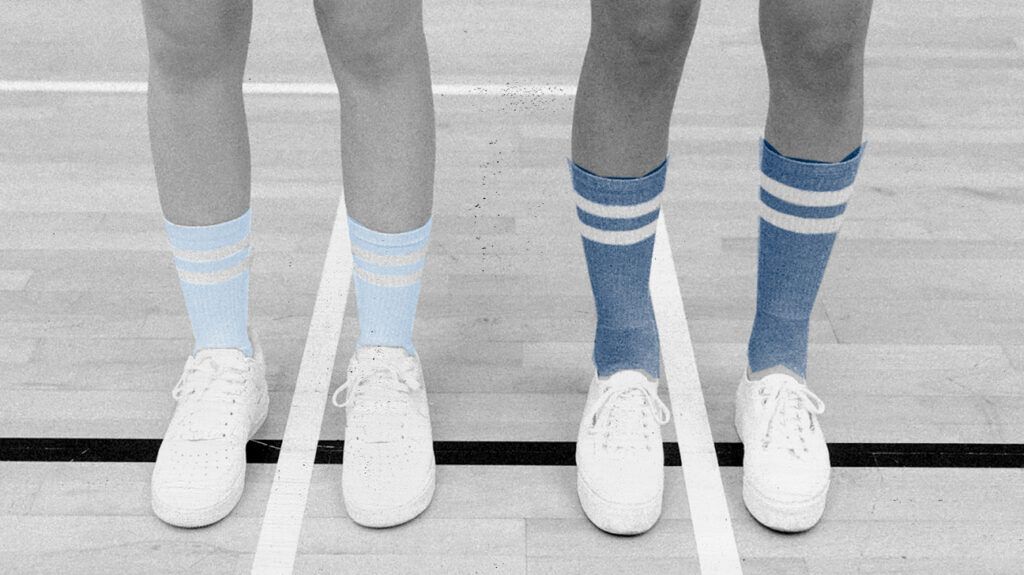 Two pairs of legs and feet wearing sports socks and sneakers.