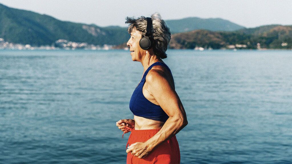 An older female with breast cancer running beside water.-2