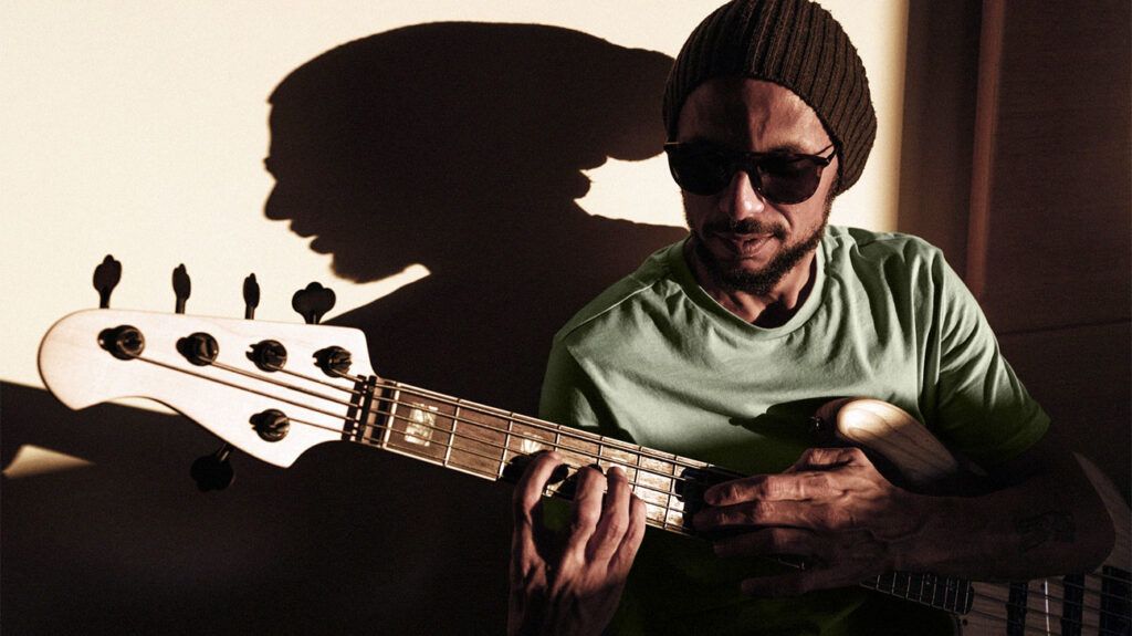 bearded man with beanie and sunglasses playing guitar