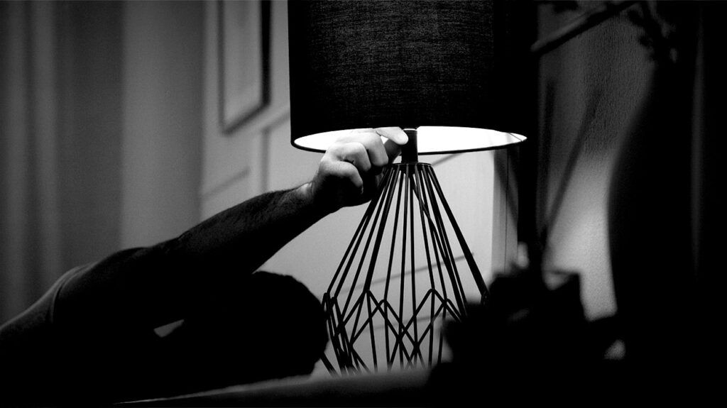 A person turning off the bedside lamp -1