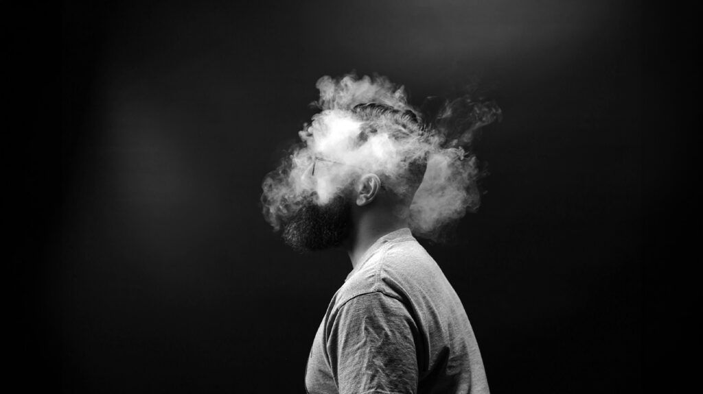 black and white photo showing person's head surrounded by smoke