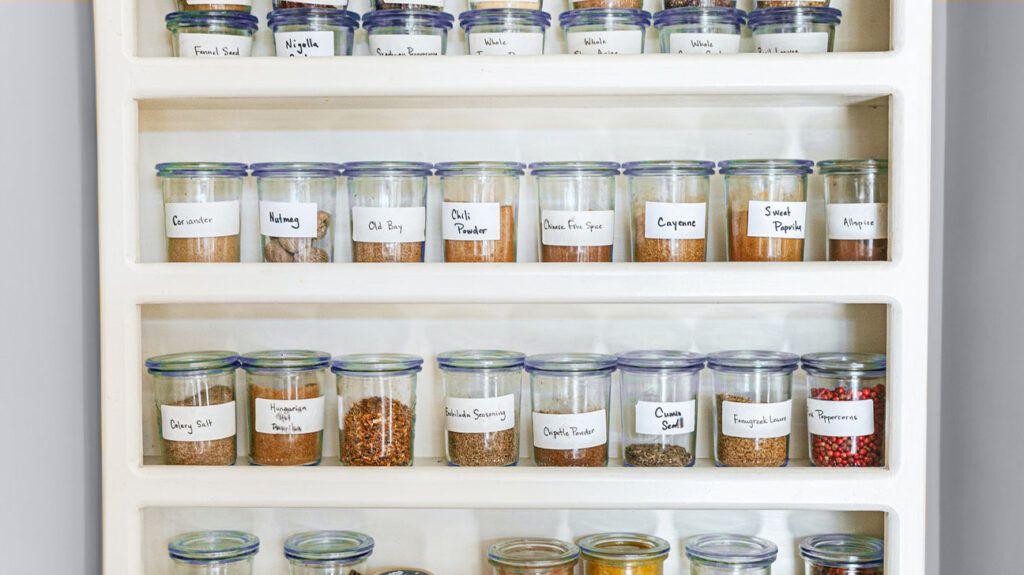 A variety of dry spices in glass jars on shelves