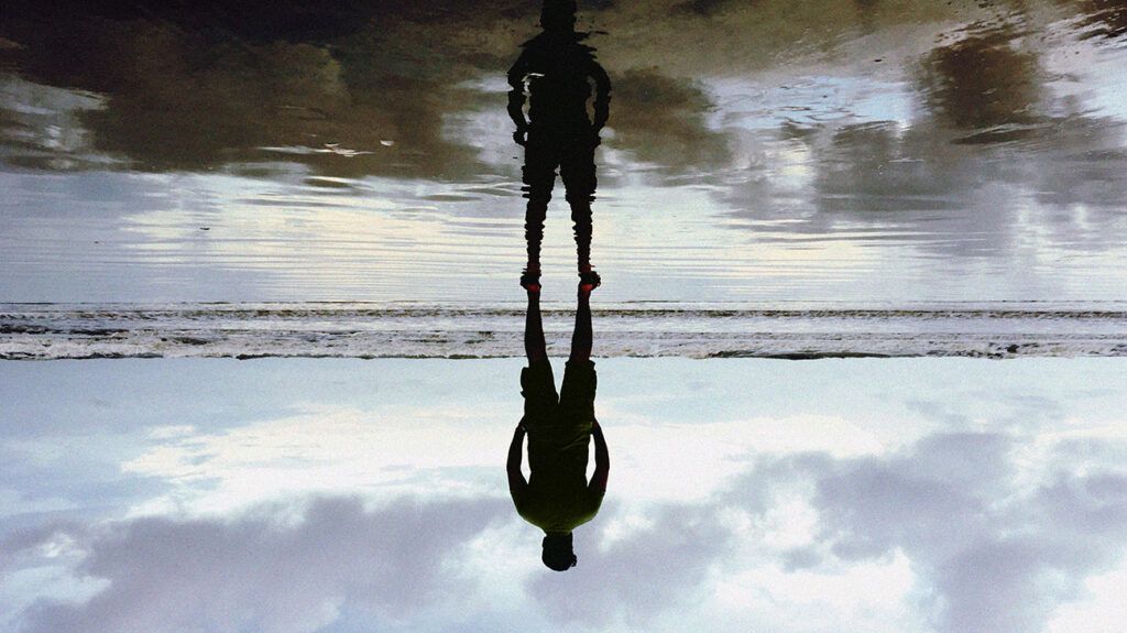 The silhouette of a person with ankylosing spondylitis and brain fog reflected on the ground.-1