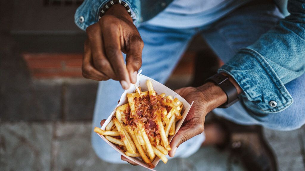 A bowl of fries in a persons hands 1