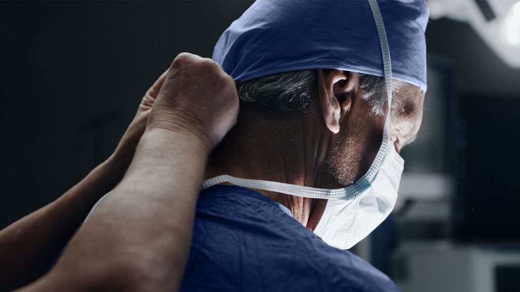 A medical assistant puts a mask on a surgeon