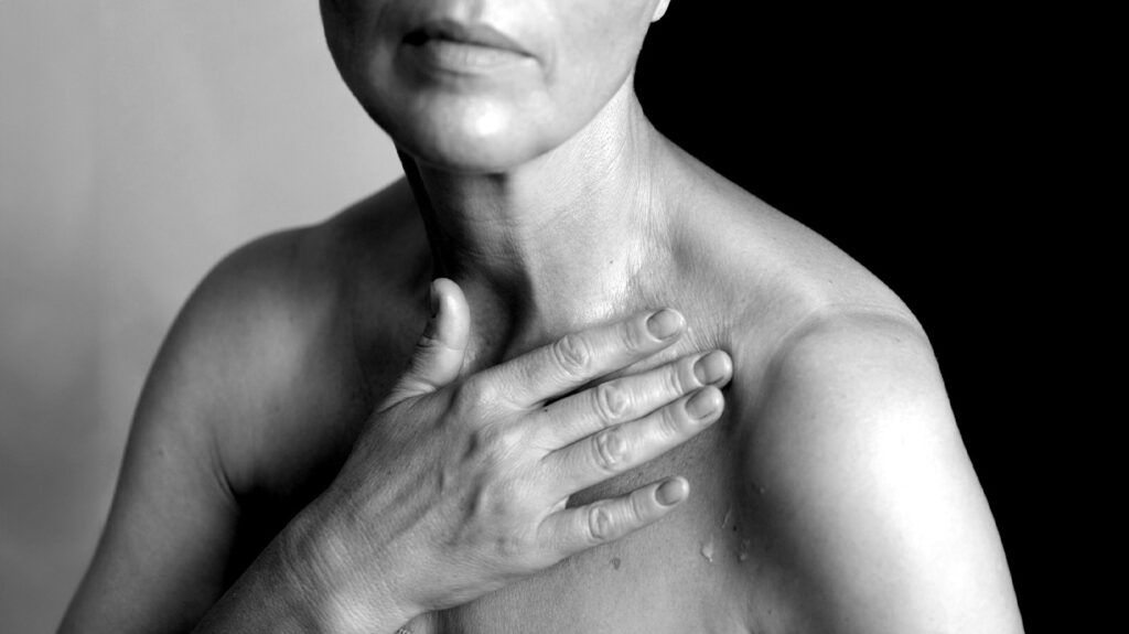 A close-up of a woman touching her collar bone