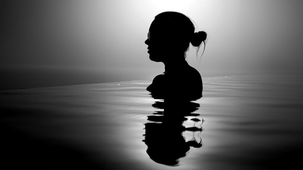 Black and white image of a silhouette of a female in the water
