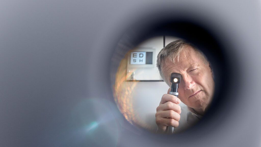 An optician examining someone through a circle lens.-1