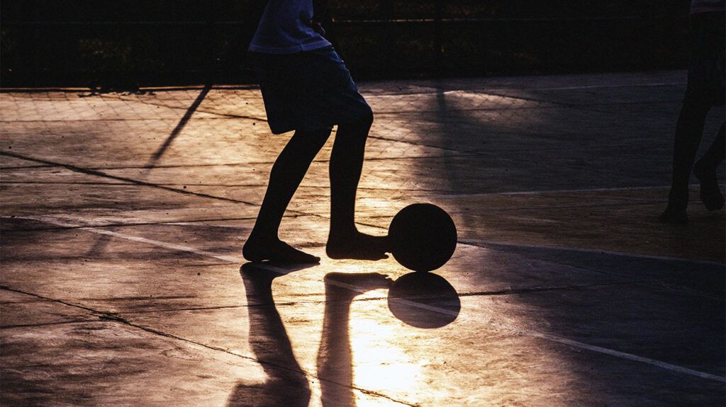 Silhouette of a young person playing soccer on the street-1