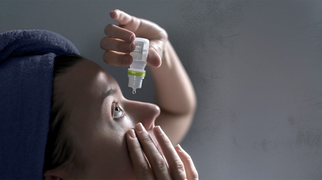 A woman applying eye drops to alleviate dry eye symptoms