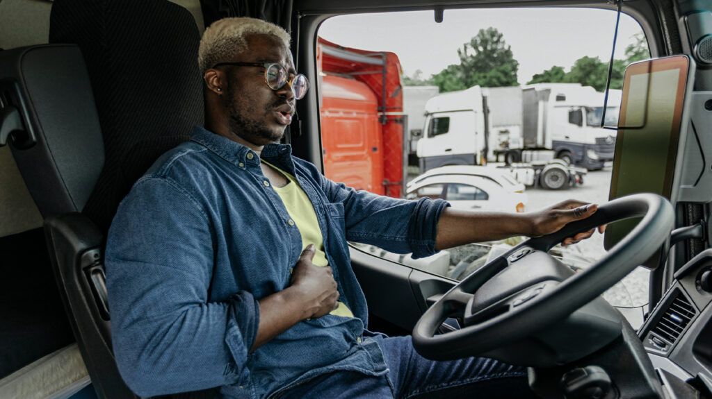 A man driving a truck while holding his stomach due to a hiatal hernia.