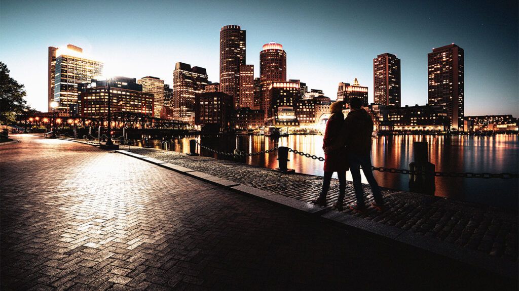 Silhouette of a couple in front of a lit up city skyline