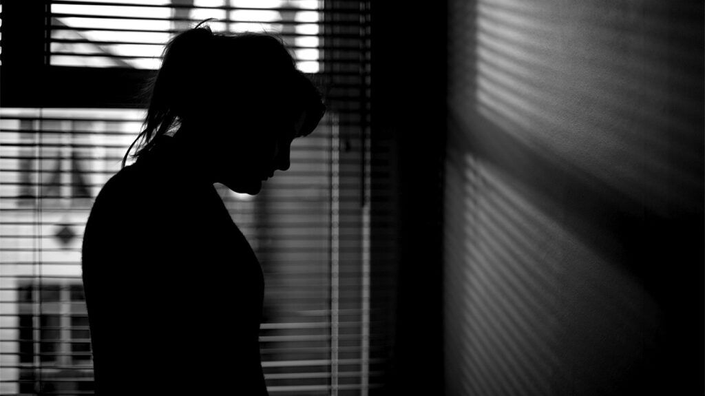 A silhouette of a woman near a window in a room