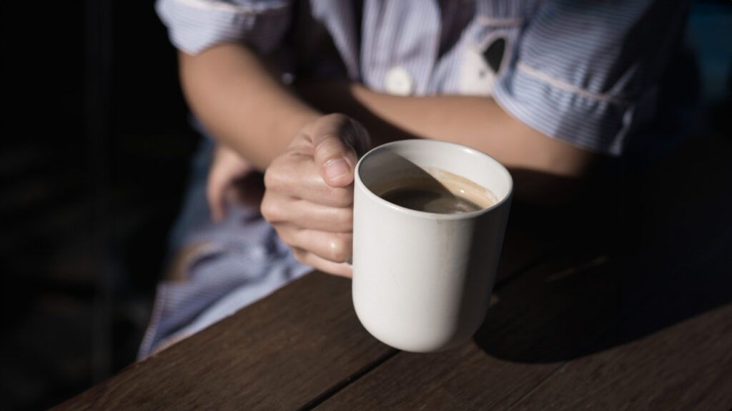 close up of a hand holding a mug of coffee