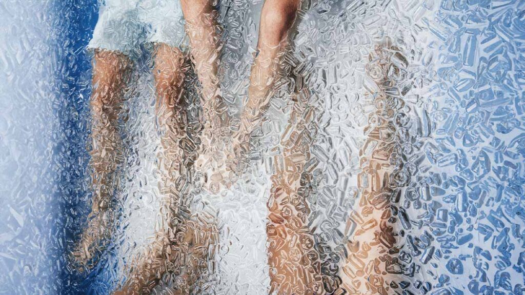 photo of three pairs of legs seen through ice water