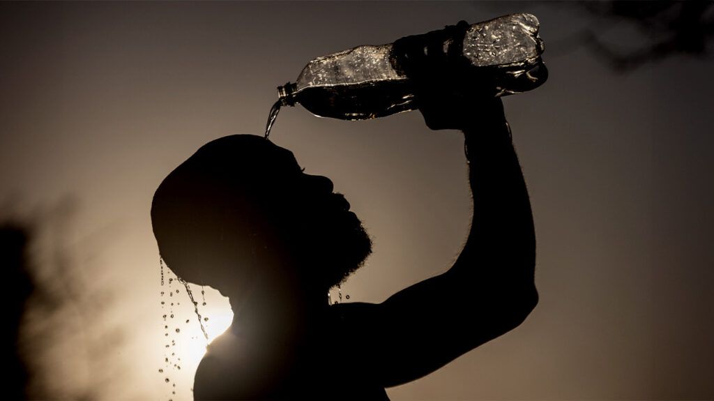 Silhouette of a male pouring water of his head