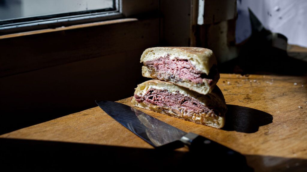 A roast beef sandwich sits on a cutting board