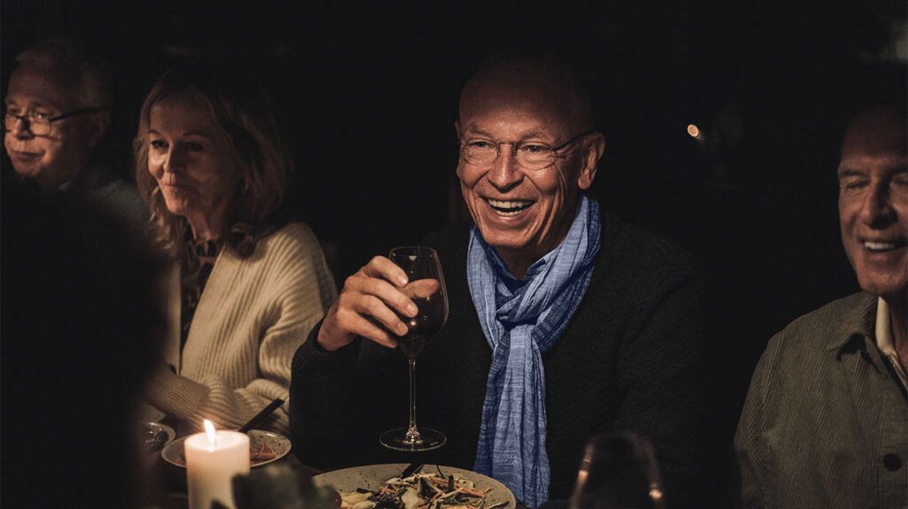 Older adults gather around a table at a dinner party